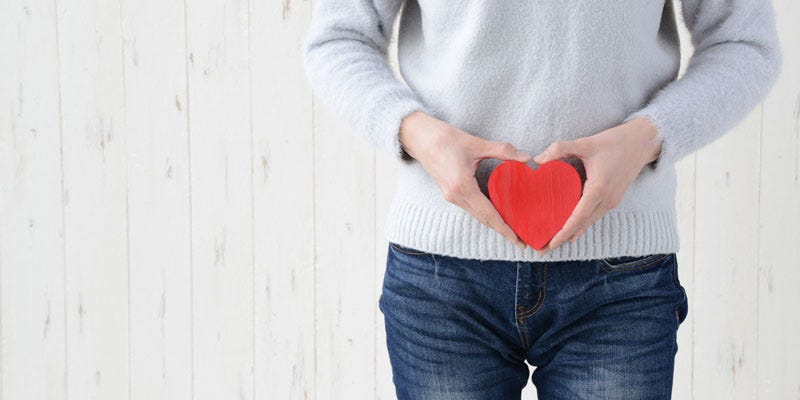 Woman holding a red heart in-front of bowels